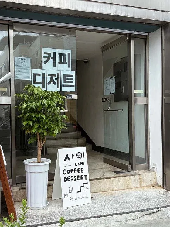 카페 사이로 올라가는 건물 입구와 안내 입간판