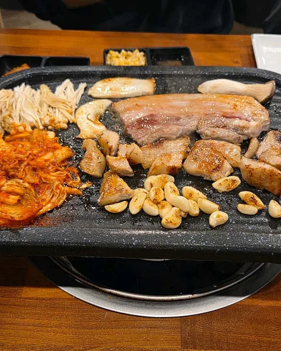 김치와 마늘을 곁들여 굽는 돼지고기 한 판