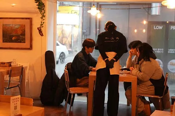 따뜻한 조명의 소코아 홍대점 실내와 식사 중인 방문객