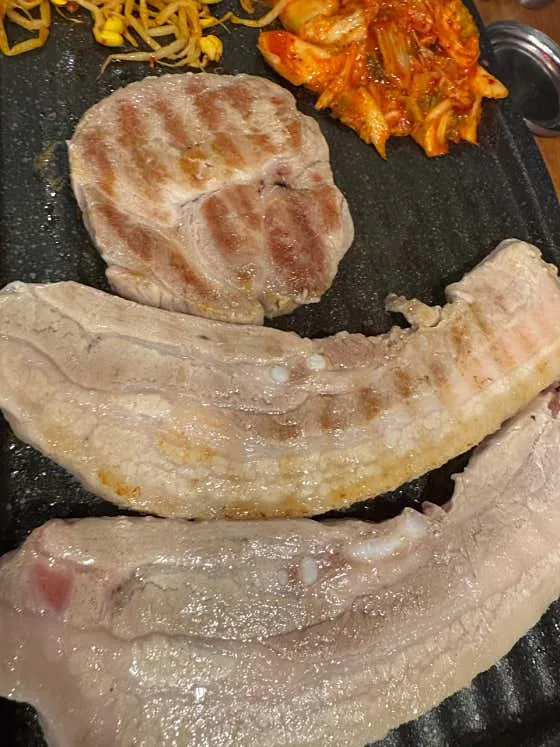 김치와 콩나물을 곁들여 익히는 두툼한 돼지고기